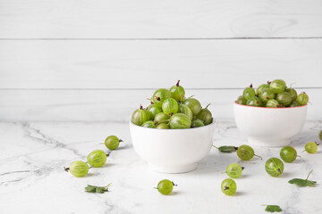 Bowls with fresh ripe gooseberry on table