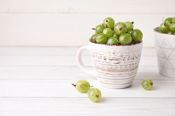 Cup with fresh ripe gooseberry on table