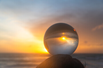 beautiful cloud and golden sunset inside crystal ball placed on a timber beside the...