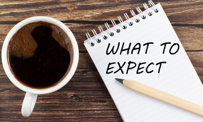 WHAT TO EXPECT text on notebook with coffee on the wooden background