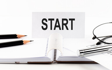 Text START on paper card,pen, pencils, glasses,financial documentation on table - business concept