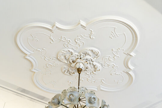 Round antique vintage decorative clay stucco relief molding with floral ornaments on white ceiling in abstract classical style interior