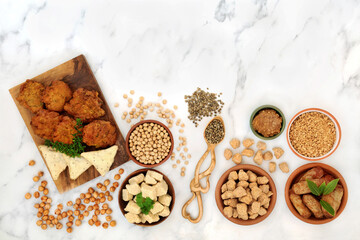 Vegan health food for a healthy diet with tofu bean curd, bhajis,  samosas, tvp, miso, soy bean, chickpeas. Plant based health foods for ethical eating concept. On marble, flat lay top view.