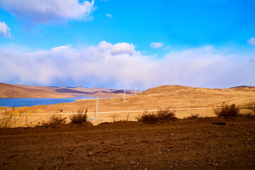 Nature landscape with golden field, wather, hills and blue sky with white clouds in a day or a evening