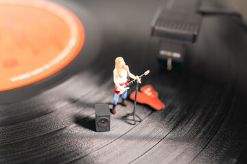Female solo miniature guitarist on a vinyl record player