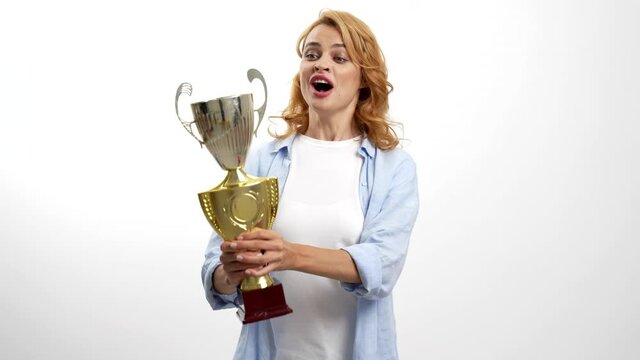 amazed happy woman celebrate victory and kiss golden cup, winner