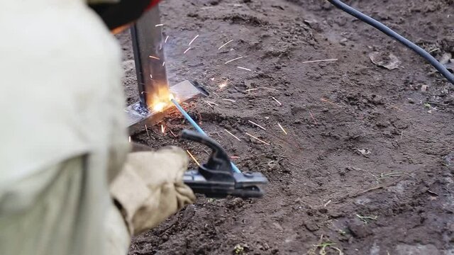 A worker welder using a welding machine welds a metal structure during construction, industry