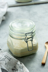 Sourdough starter in a jar, yeast-free leaven starter for healthy organic rustic bread, home baking concept