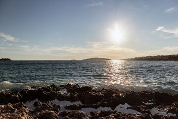 Beautiful summer sunset over small town of Rogoznica, with open Adriatic sea splashing the rocky shore