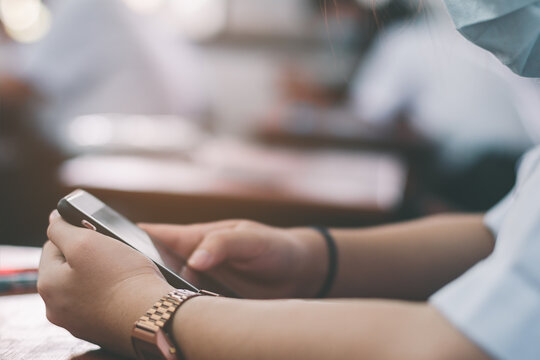 Uniform students are test exam and study online by using smartphone and wearing protective facemask in classroom