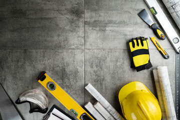Contractor theme. Plans, tool kit of the contractor, yellow hardhat and libella. Gray tiles...