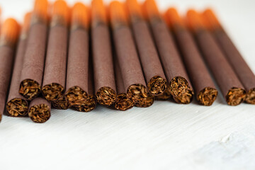 Cigarettes with a filter, wrapped in brown paper, on a white background close-up