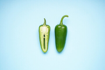 Jalapeno peppers, whole and sliced on a blue background. Top view.