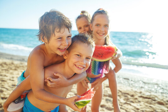 Children with a watermelon at the sea. A group of children have fun playing at the sea. High quality photo