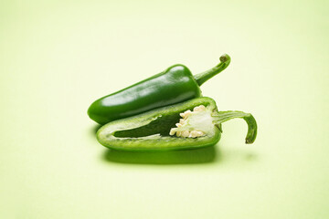 Jalapeno chili peppers, whole and sliced on a green background, close-up.