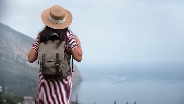 Back view backpacker travel woman admiring nature scenery mountain top over sea relaxing freedom