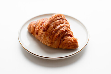 Freshly baked croissant with caramel filling on plate in a cafe