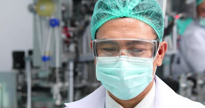 Asian man manager in sterile cloths working on laptop computer in fodd production line factory. Surgical Face mask production