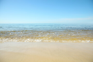 Fototapeta na wymiar Sea wave rolling on sandy beach in summer, closeup