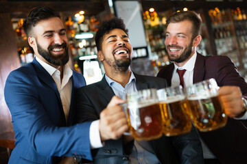 Team of colleagues socializing at the bar and drinking beers