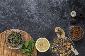 Different types of tea on a gray background, with lemon, mint and herbal lollipop