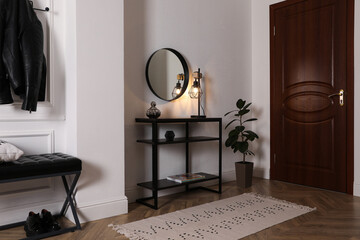 Console table with decor and mirror on white wall in hallway. Interior design