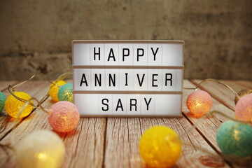 Happy Anniversary text on lightbox on wooden background
