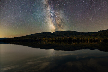 Starry night sky. The milky way is reflected in the lake. The mountains are sleeping peacefully. 