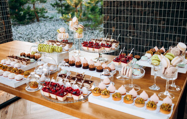 Delicious candy bar at luxury wedding reception. Exclusive expensive catering. table with modern desserts, cupcakes.