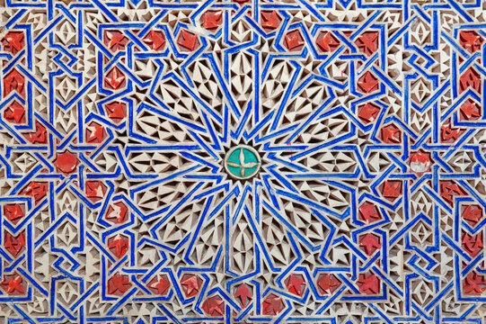 Intricate carved stonework, abstract Arabesque motif as part of the Moroccan design and architecture, symmetrical pattern with painted details of scrolling and interlacing lines in Marrakech, Morocco
