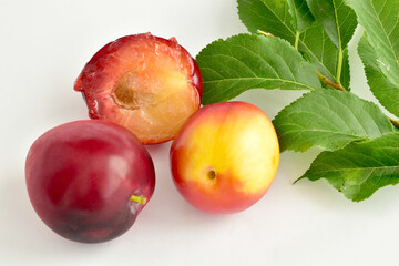 Ripe, juicy cherry plum fruit and one half of this fruit lie on a white table