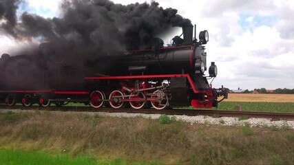 Vintage coal steam locomotive with smoke on trail. Retro transport and travel. Historic train on railroad.