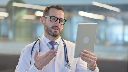 Video Chat on Tablet by Young Male Doctor