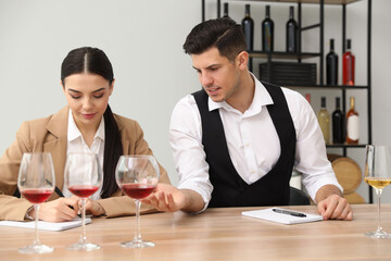 Sommeliers tasting different sorts of wine at table indoors