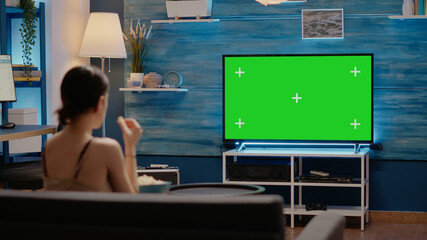 Green screen on modern television display at home in living room. Caucasian young woman watching...