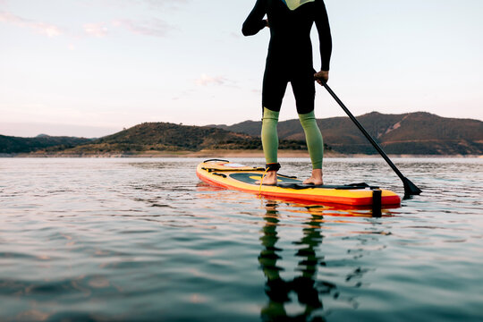 Unrecognizable man floating on paddleboard in sea