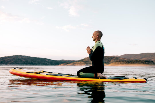 Man practicing yoga on SUP board in sea
