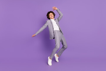 Photo of carefree small guy stand tiptoes dance have fun wear grey suit isolated violet color background