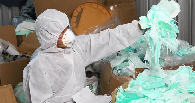 Man inspector in protective suit (PPE) collecting and checking samples of surgical face mask