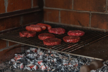 Cocinando al aire libre, una barbacoa de hamburguesas y chorizo criollo. Parrillada de verano al calor con la piscina. Fuego, brasas y mechero. Carbón Quema Madera y ceniza de fuego mangal barbeque