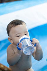 Cute Asian boy naked and is drinking from a water bottle