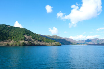 Range of mountain covered with green forest against blue clouds sky background in sunny day,Lake Ashi or Hakone Lake in Japan.