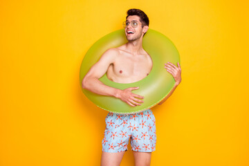 Photo of cool funny guy shirtless arm dark glasses holding water circle looking back empty space isolated yellow color background