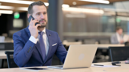 Middle Aged Businessman with Laptop Talking on Phone