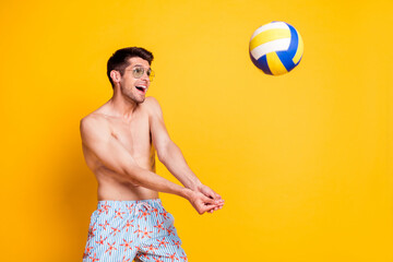 Photo of funny pretty young man naked torso dark eyewear playing volleyball smiling isolated yellow color background - Powered by Adobe