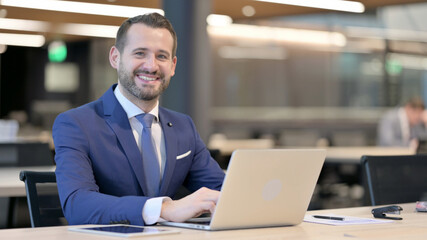 Fototapeta premium Middle Aged Businessman with Laptop Smiling at Camera