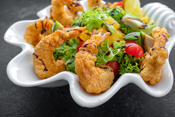 Japanese Cuisine - Tempura Shrimps shrimp in tempura with lemon slices and salad on a black background