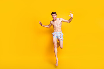 Fototapeta na wymiar Full length body size view of attractive cheerful shirtless guy jumping running having fun isolated over bright yellow color background