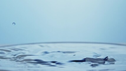 Slow-motion close up of an ice cube falling in a drink creating blue splashes. slow motion - Powered by Adobe