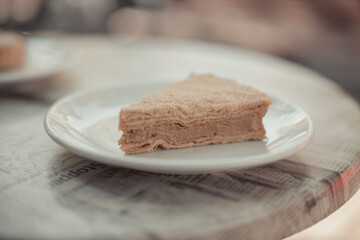 A piece of homemade napoleon cake with cream on a table in a street restaurant. Tasty morning food